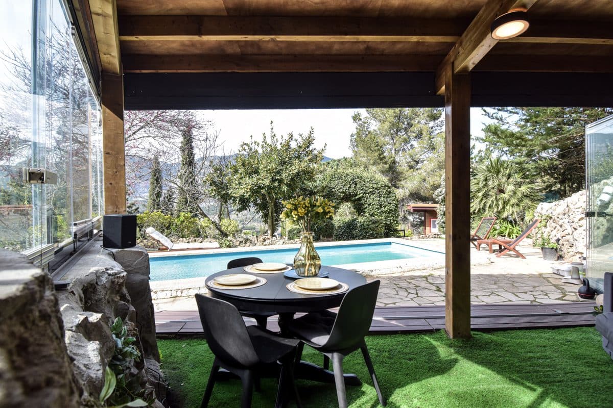 The covered terrace outside Dragonfly, table laid, the pool and garden beyond.