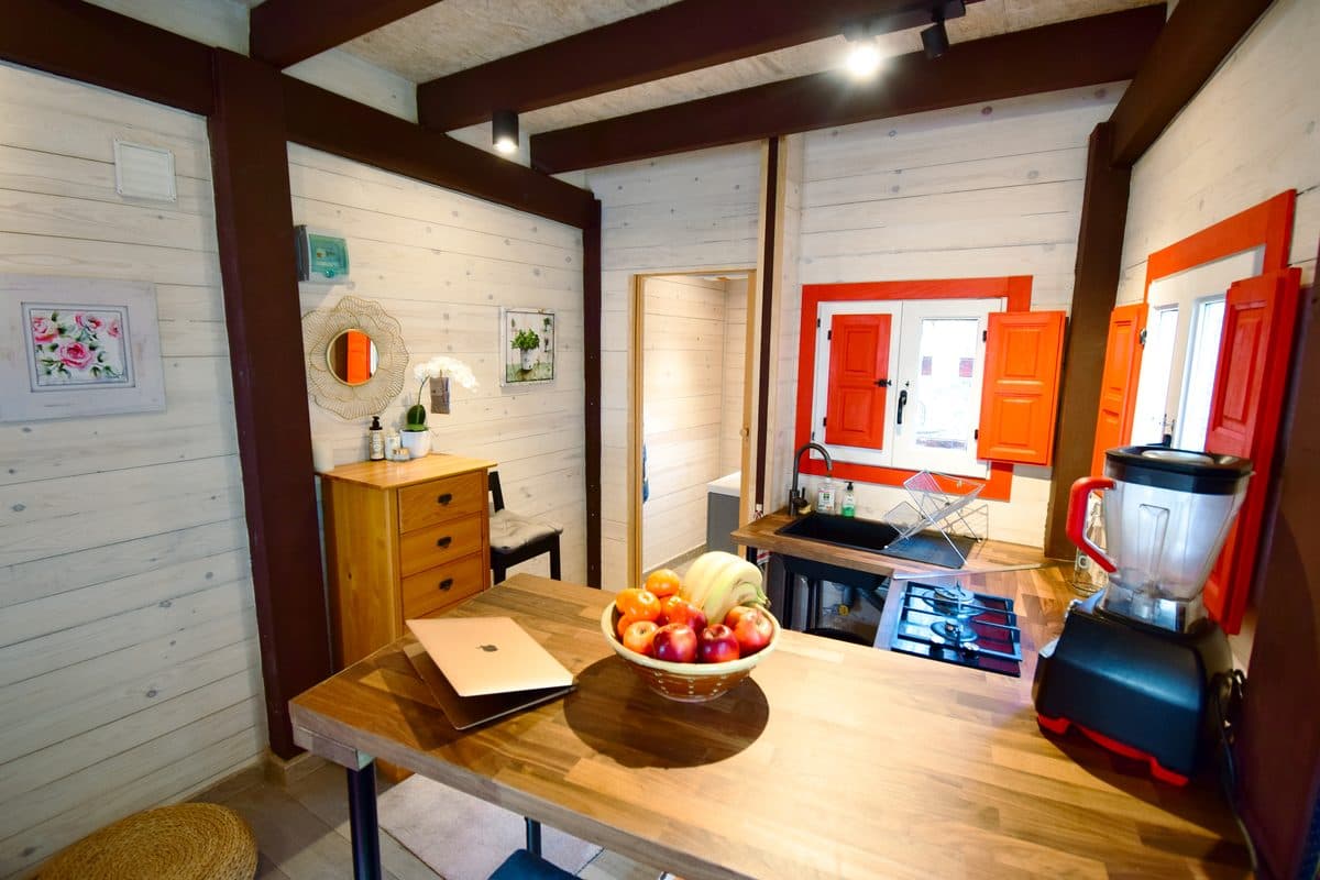 The guesthouse kitchenette: a wooden breakfast bar, gas hob, and red-shuttered windows.