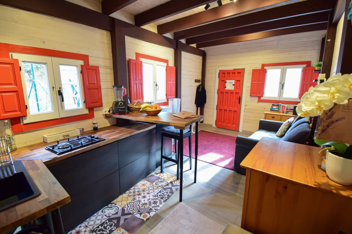 The guesthouse living end: red front door, blue sofa, bookshelf, red shutters.
