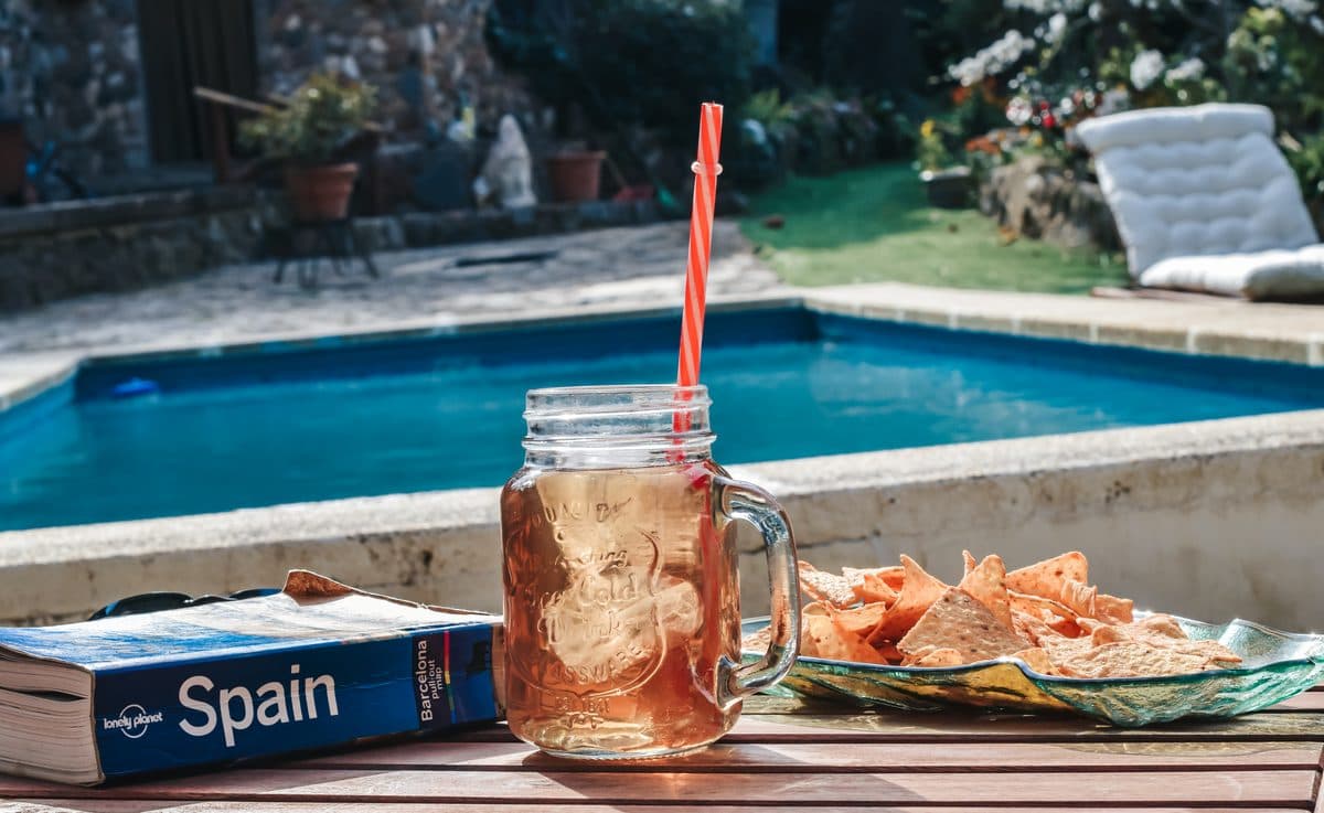 Iced tea and a guidebook on the pool edge, the stone house behind.