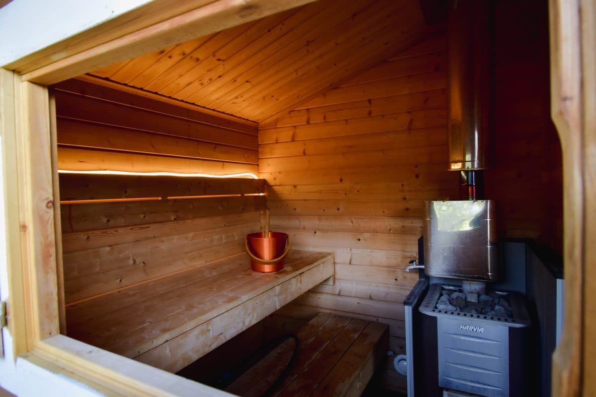 Inside the sauna: the Harvia wood stove, the lit bench, a bucket and ladle.